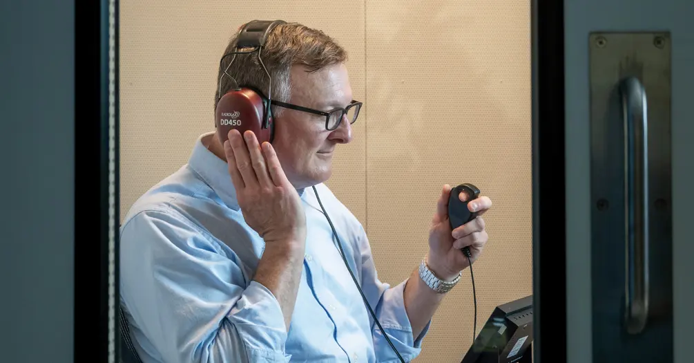 Rick Neitzel demonstrates testing in an audiometric test booth.