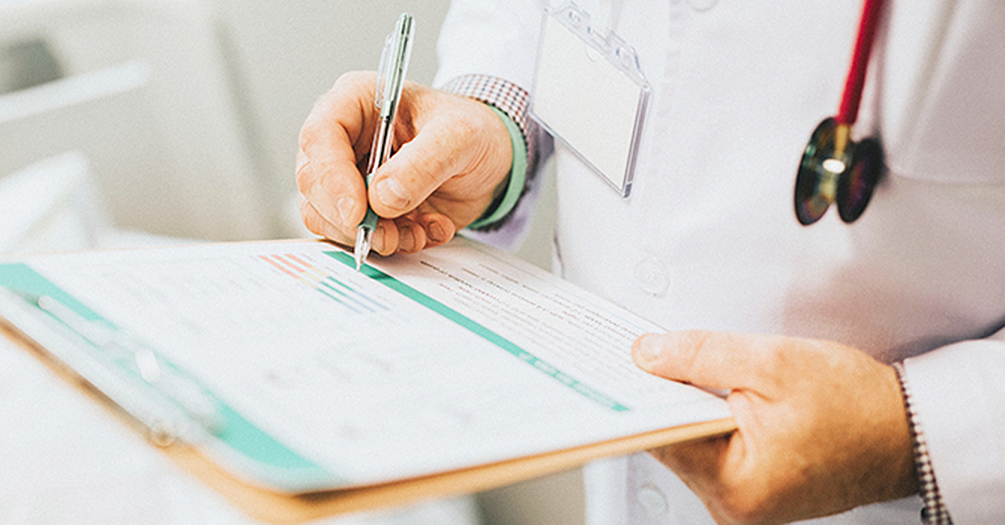 A doctor writes on a clipboard