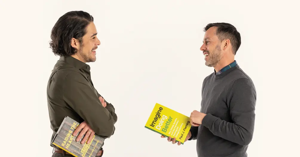 Bill Lopez, left, and Paul Fleming looking at each other, each holding a copy of their own books