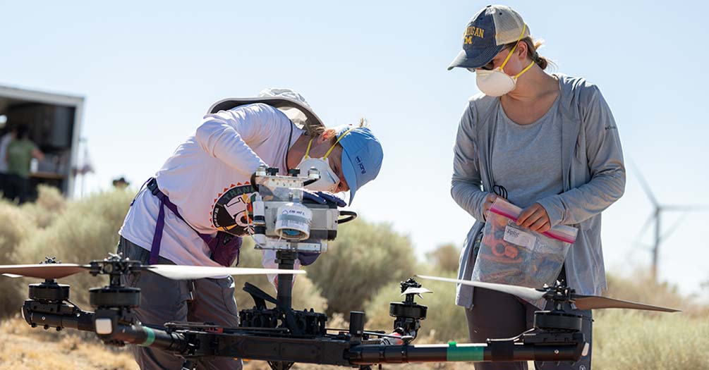 Jennifer Head, left, and student researcher Sarah Dobson load an air filter on a drone in order to sample air for Coccidioides. (Photo credit: Yuan Zhu)