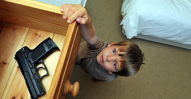 Child reaching into drawer with gun