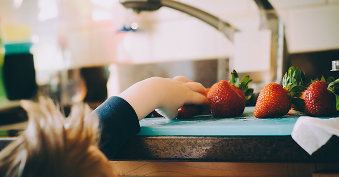 child reaching for strawberries