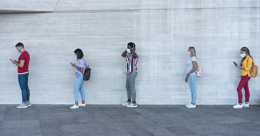 Young adults standing in a socially distanced line.