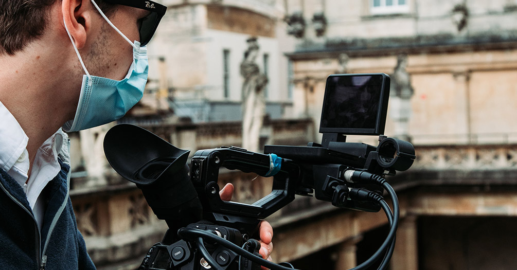 person wearing a mask operation a video camera