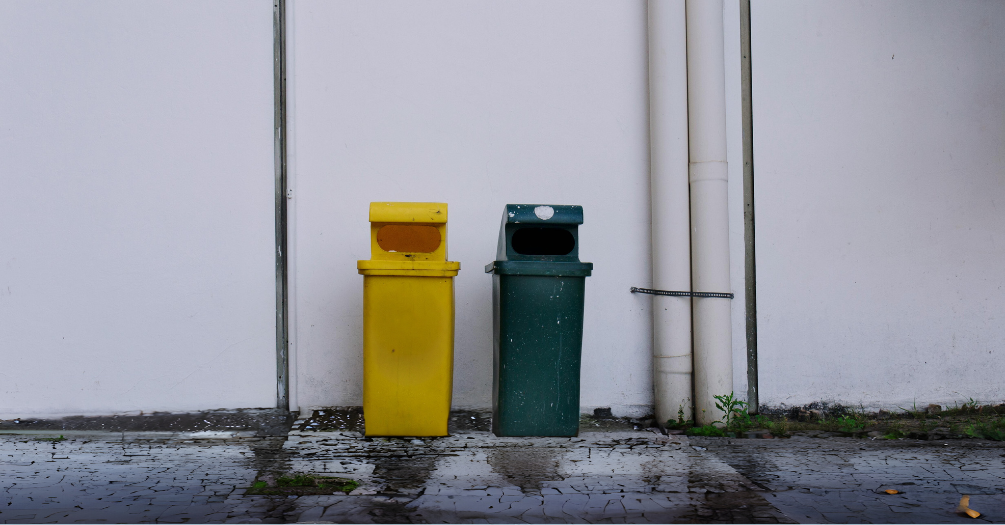 Two plastic bins on a rainy street. 