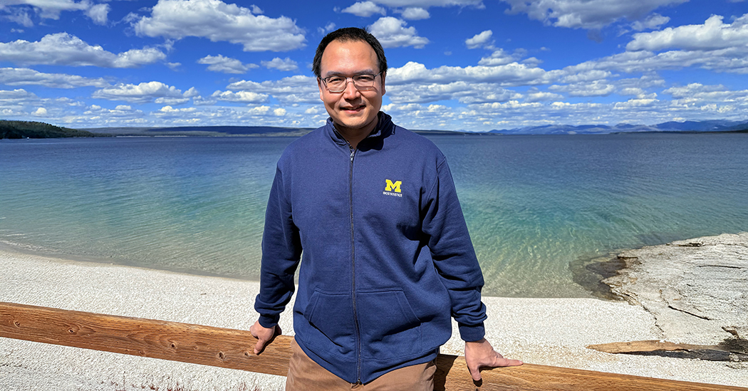 Jian Kang in front of a body of water