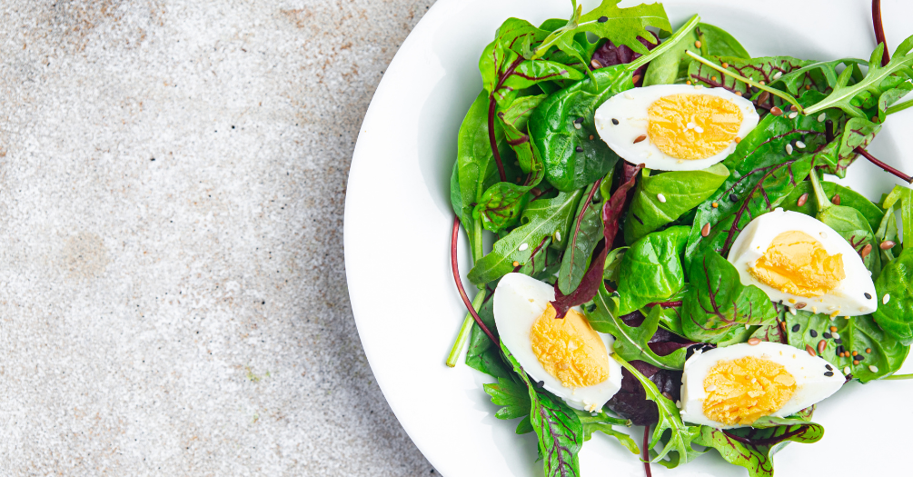 A leafy green salad topped with sliced, boiled eggs.