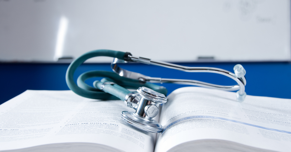 A stethoscope lies on an open textbook in a nursing classroom