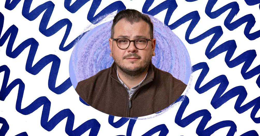 Michael Shepherd headshot, framed within an light blue oval on a white and blue patterned background.