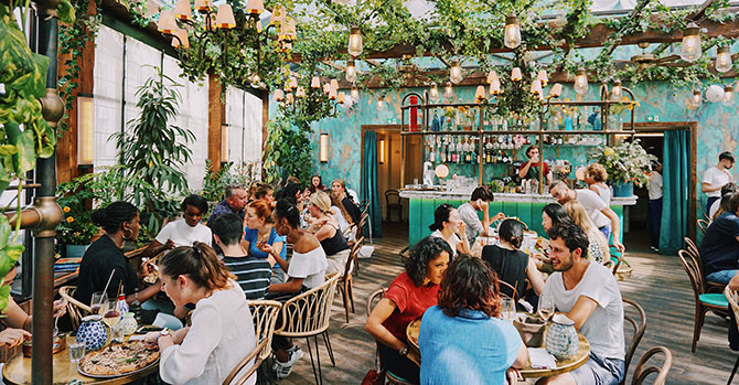 Outdoor restaurant with many gathered at tables. 