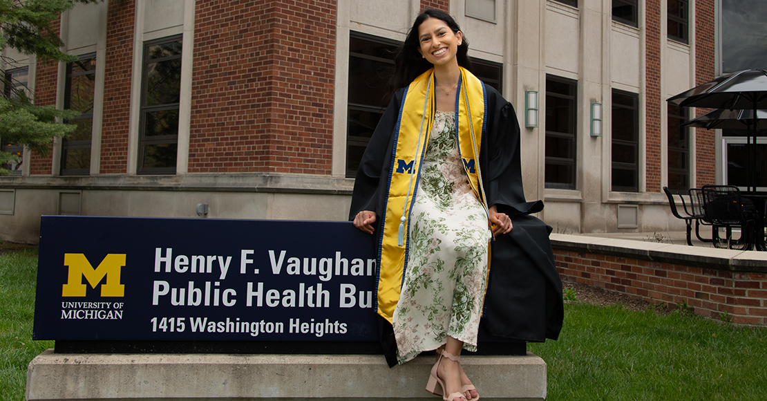 Aparna Reddy sitting on the Henry F. Vaughan Public Health Building sign